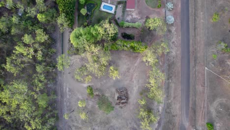 toma de arriba hacia abajo de la finca rural con una gran casa roja, piscina, estanque, jardines de piedra y césped verde
