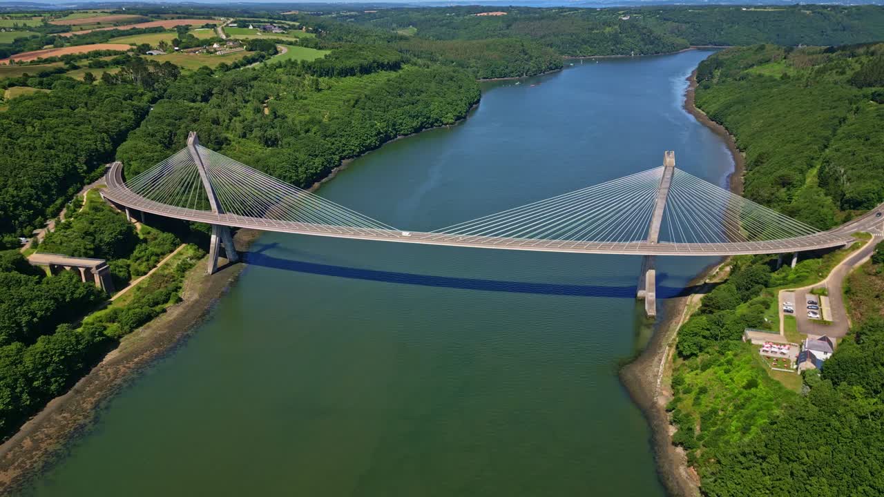 Modern Térénez Bridge over Aulne River surrounded by lush green forest and countryside, Brittany, France. Aerial drone panoramic view