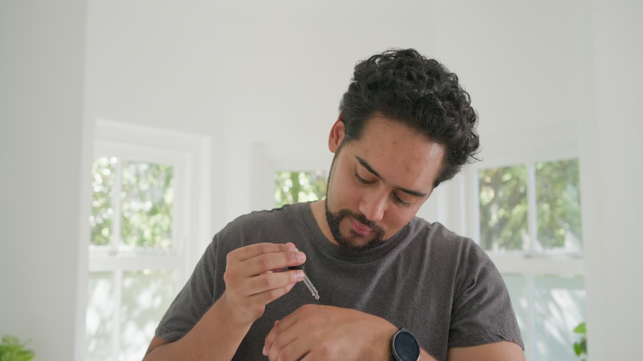 Vertical video: Man feeling cheek reaching pipette putting serum rubbing face showing care routine