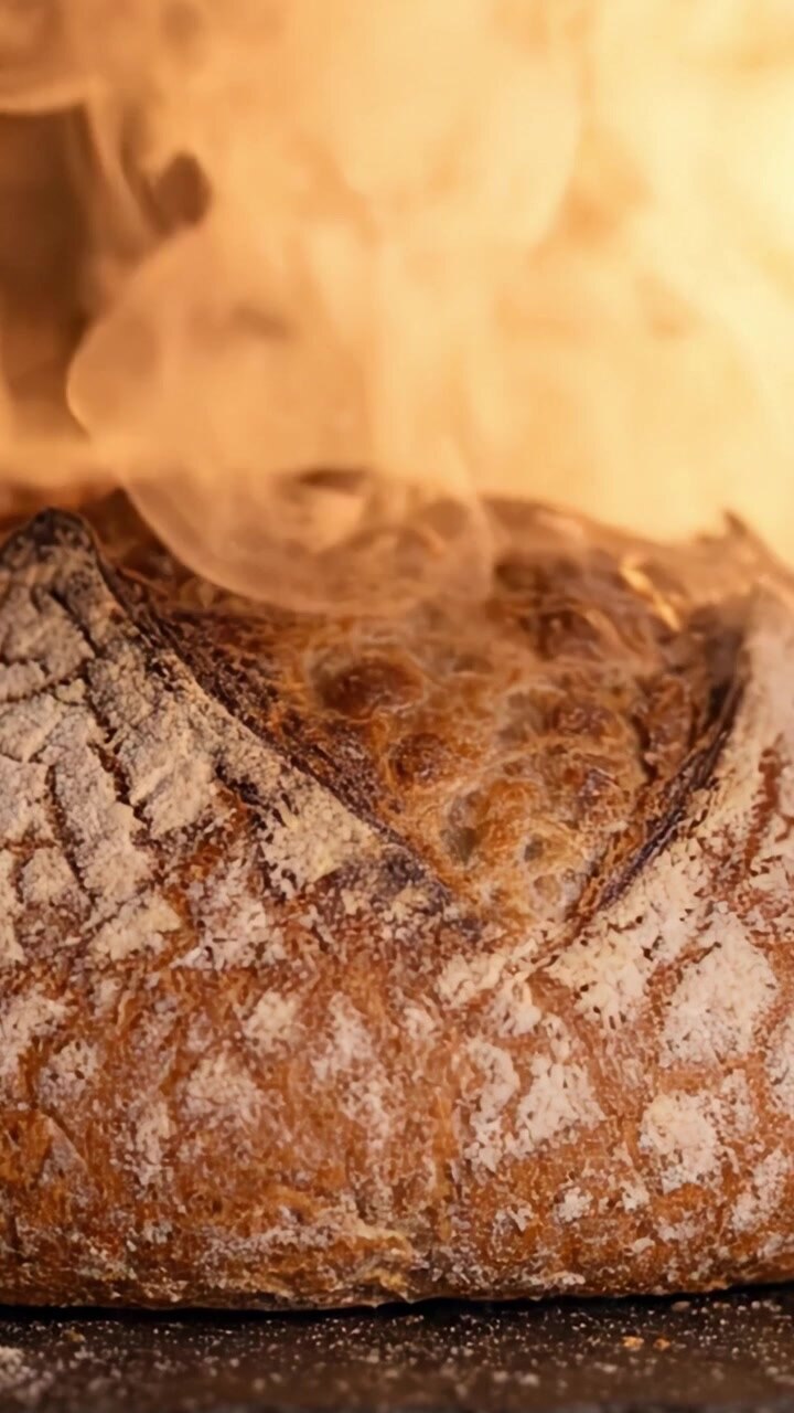 The Art of Baking Bread: A Close-Up of a Rustic Loaf Perfectly Crusted and Rising in the Warm Glow of the Oven's Heat