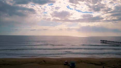 vuelo aéreo sobre la playa de california después de la tormenta, la luz del sol brilla a través de las nubes