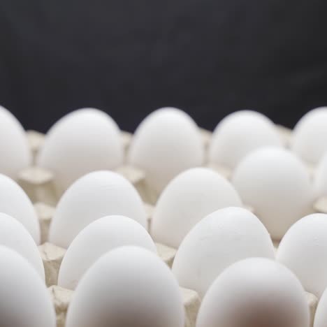 hand puts eggs in a box. eggs are stacked in a tray.