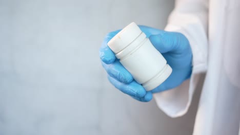 un médico con un frasco de pastillas blancas