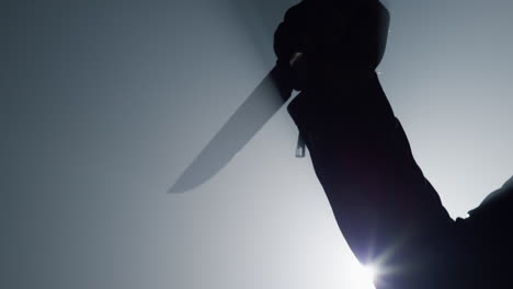Silhouette-criminal-hand-attacking-with-knife-in-darkness.-Arm-holding-weapon