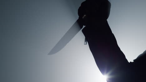 silhouette criminal hand attacking with knife in darkness. arm holding weapon