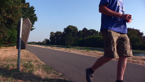 man-throwing-an-empty-plastic-bottle-in-a-garbage-bin-near-a-water-channel-while-smoking-cigarette