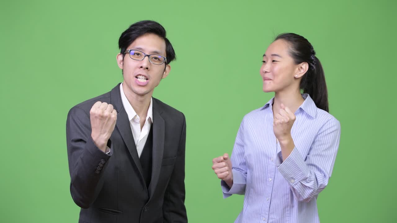 Young Asian business couple getting good news together
