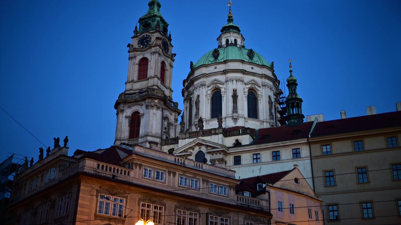 La cupola barocca e la torre dell'orologio della Chiesa di San Nicola sopra i tetti di Malá Strana all'ora blu, Praga, Repubblica Ceca