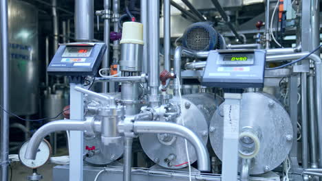 approaching to the steel faucets with sensors at the milk plant. shining metal equipment of the dairy factory. close up.
