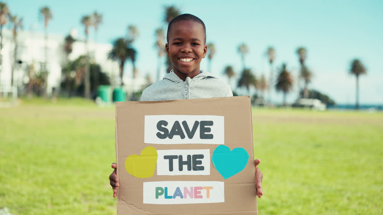 Bambino, volto felice e cartello di protesta ecologico