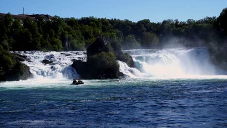 panoramic shot of rheinfall waterfall switzerland, boat passing in front of cascades