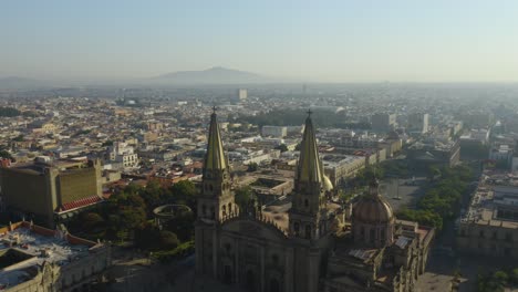 drone flies between guadalajara cathedral steeples on smoggy morning