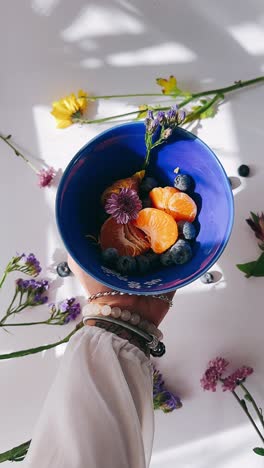 woman holding a bowl of fruit salad with flowers