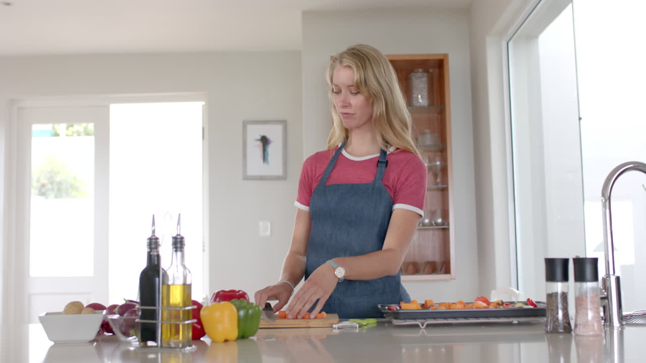 retrato de una feliz mujer caucásica con delantal y cocinando en la cocina, en cámara lenta