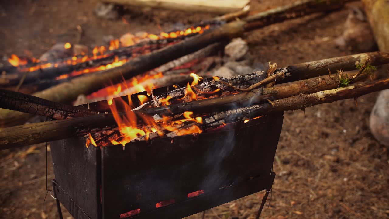 Bonfire, fire flames in barbecue. Campfire, campsite in the background. Daytime.
