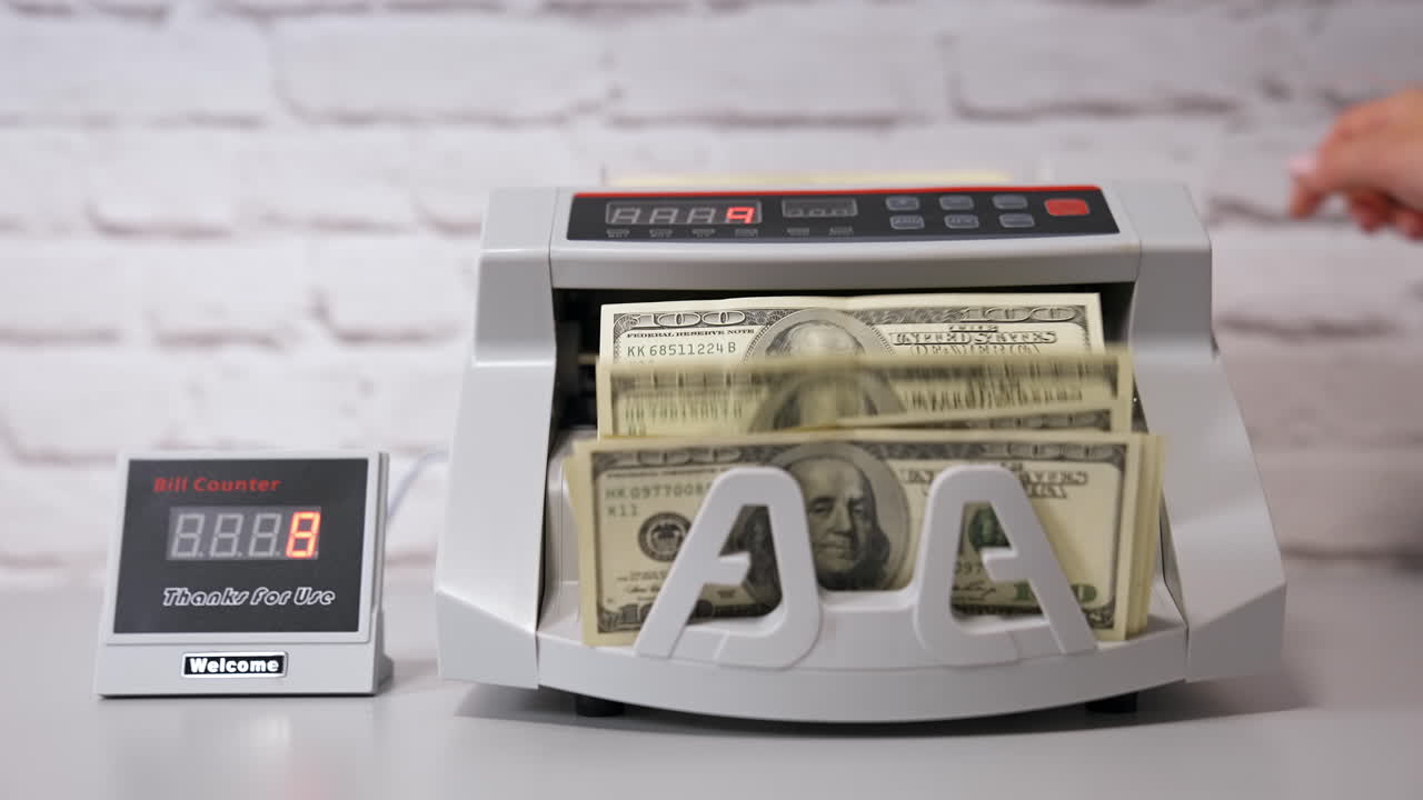 Electronic cash counting machine. Bank financial operations and calculating dollar banknotes. Female hand puts paper money into automatic equipment for counting bills.