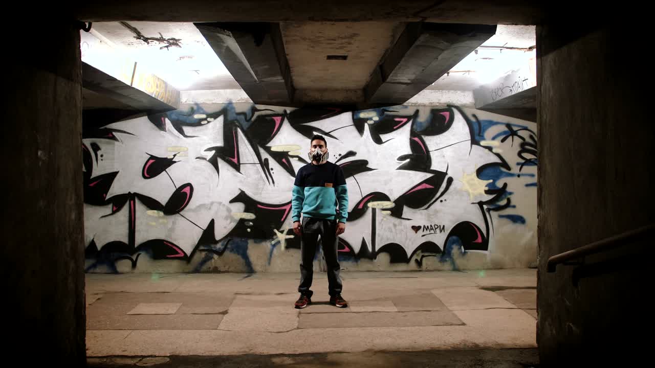 Portrait of graffiti artist painting in subway on graffiti background