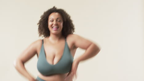 young biracial plus size woman with curly hair smiling in studio, copy space