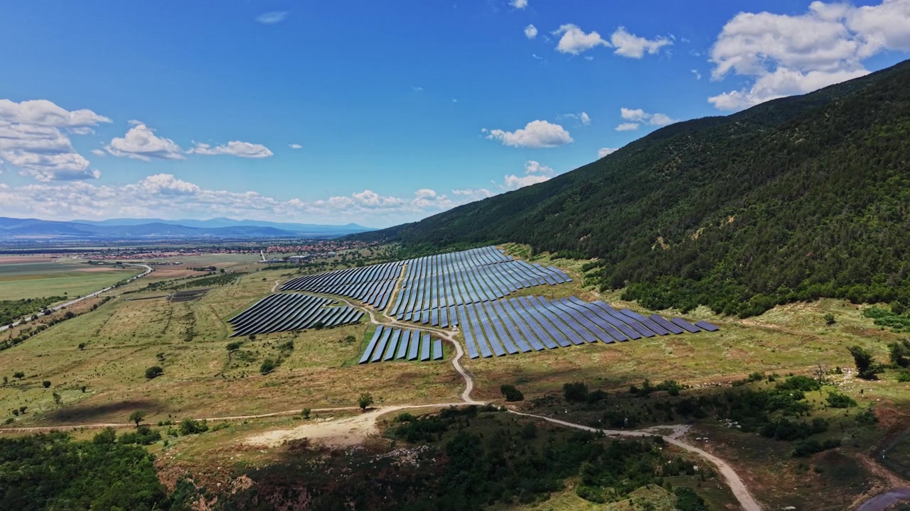 Solcellepaneler dækker et stort område på landet under en blå himmel