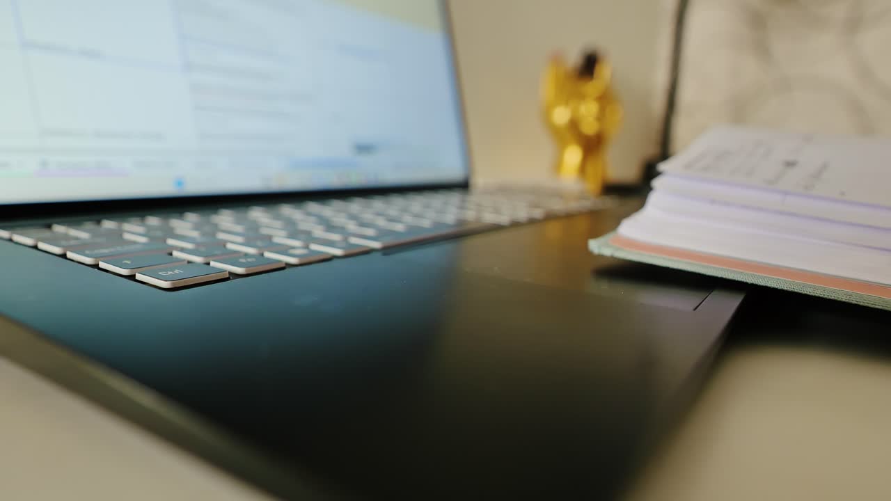 Macro detail of keyboard corner with blurred notebook and golden pen holder