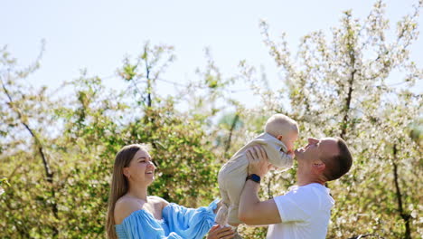 caucasian parents toss their little son. happy family spending time together outdoors in spring.