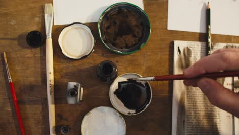 male artist putting ink on a brush, top view