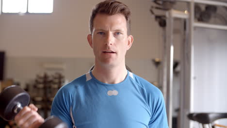 man working out with dumbbells at a gym, front view close up