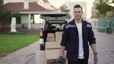 Junger,-Gutaussehender,-Lächelnder-Kaukasischer-Liefermann-Mit-Kisten-Auf-Dem-Wagen,-Der-Aus-Einem-Lieferwagen-Mit-Geöffnetem-LKW-Kommt.-Männlicher-Postangestellter