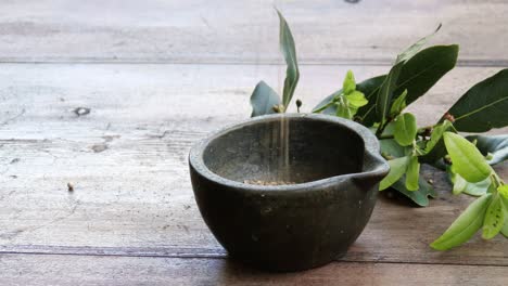 Pouring-coriander-into-a-solid-brass-mortar-before-grinding,-close-up