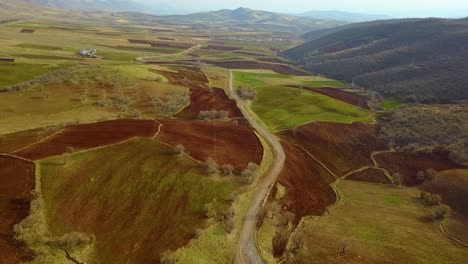 Fly-over-farm-land-field-in-summer-landing-on-agriculture-ground-wide-view-of-country-village-and-mountain-landscape-in-Zagros-range-in-Iran-fields-of-rice-wheat-and-fresh-products-in-food-industry