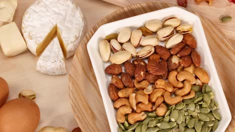 a selection of nuts, cheese, and eggs arranged on a wooden surface.
