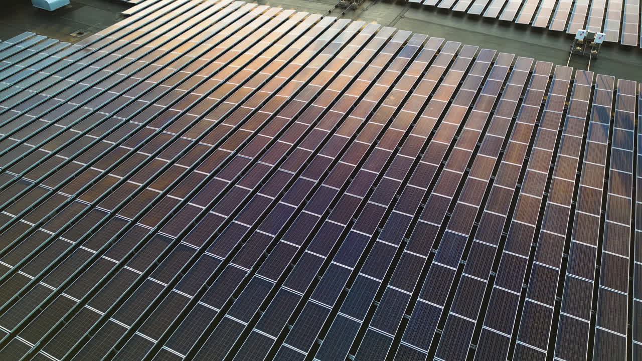 Reflection of sunlight on solar panels installed on roof of large building. Sunset time on Cook Islands. Aerial top down flyover. Modern Innovation and Development on tropical island.