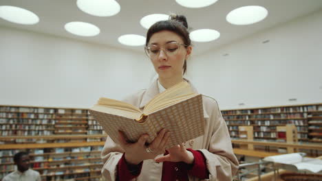 young woman reading book in library