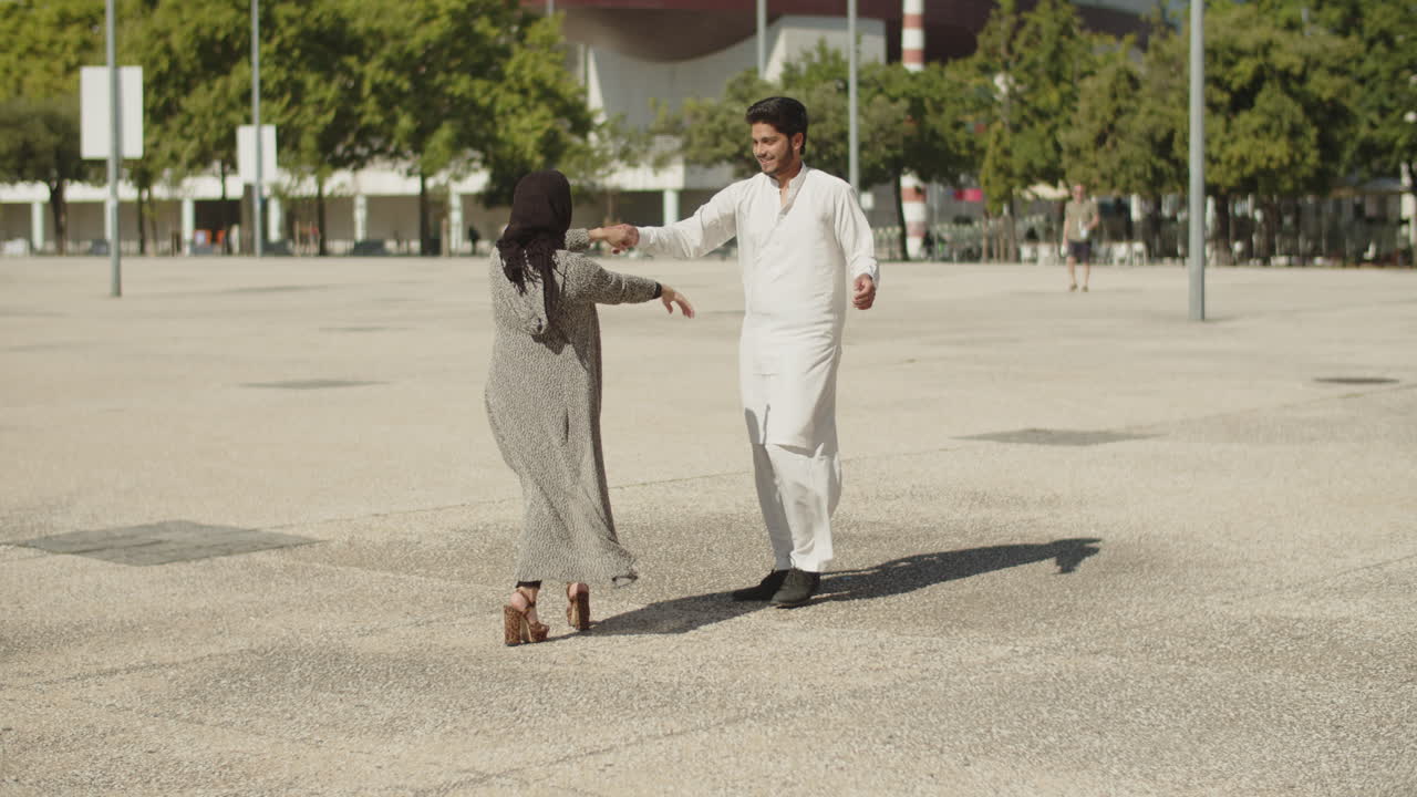 Romantic muslim couple dancing together in street on sunny day.