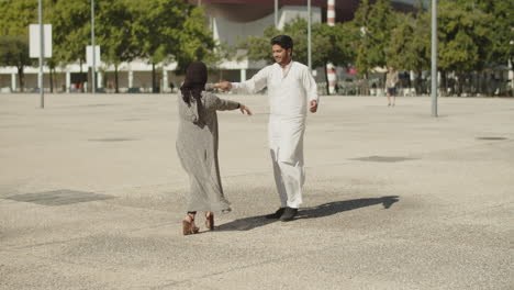 romantic muslim couple dancing together in street on sunny day.