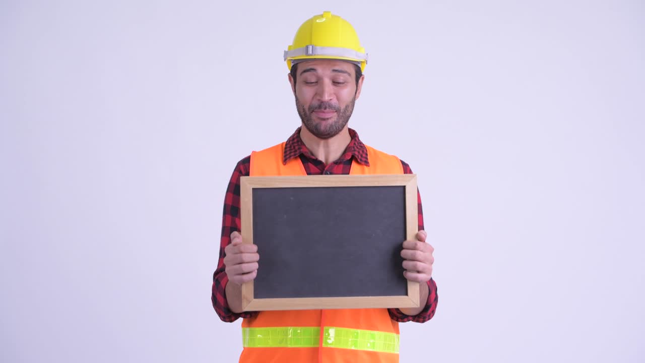 feliz hombre persa barbudo y guapo trabajador de la construcción con pizarra