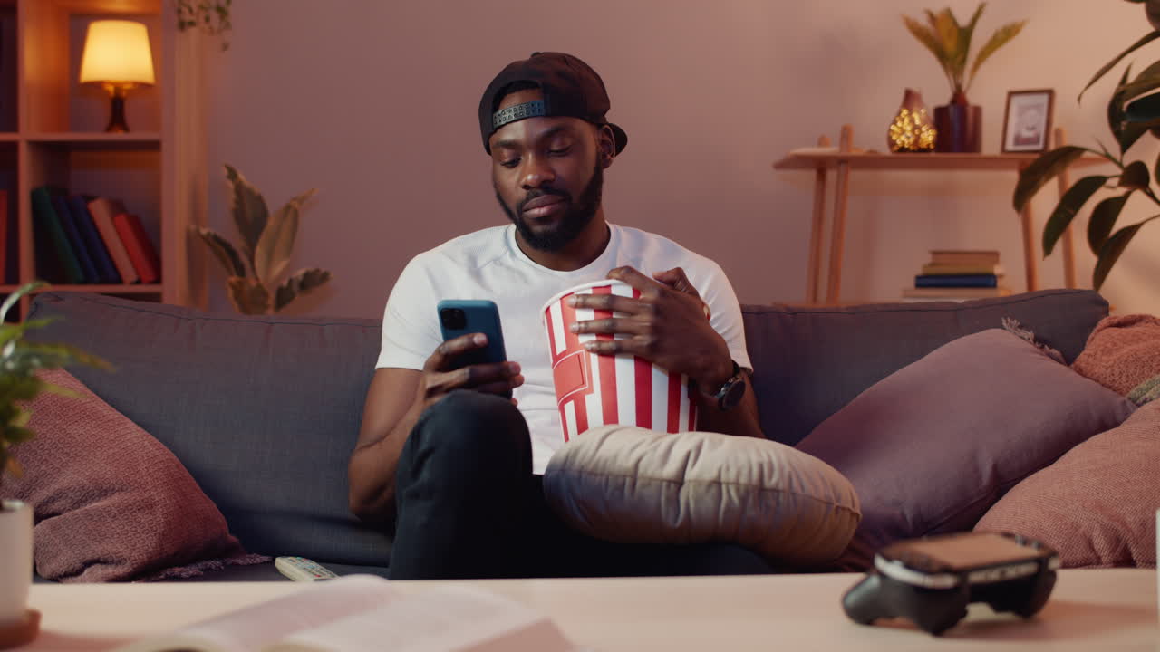 Man watching movie on sofa eating popcorn