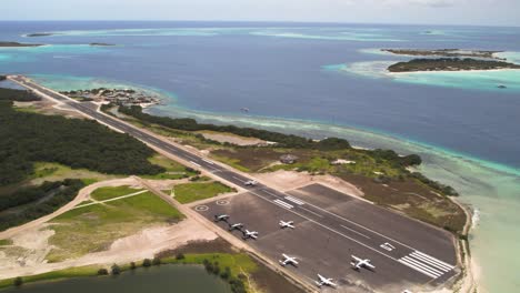 Planes-at-gran-roque's-airstrip-by-the-blue-sea,-during-the-day,-tropical-vibe,-aerial-view