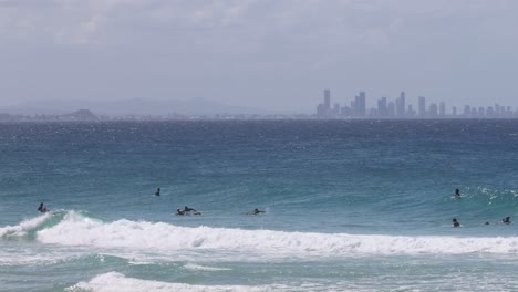 surfers riding waves with city skyline in background