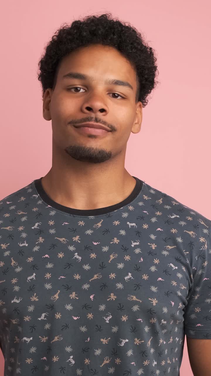 Smiling young man looking at camera in pink studio