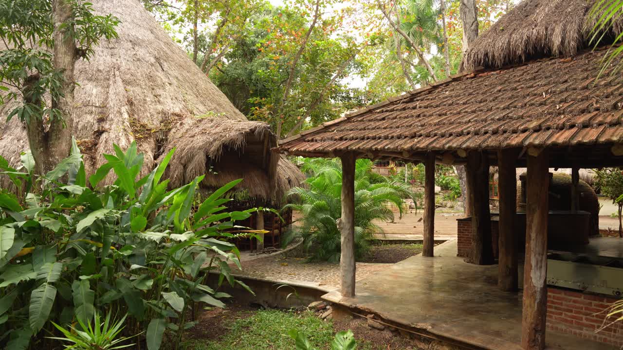 Traditional thatched-roof huts surrounded by lush tropical in a rustic eco-lodge in Yucatan, Mexico.
