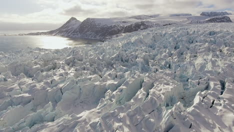 Large-glacier-reflecting-off-sunny-day-in-winter,-close-up-drone-shot