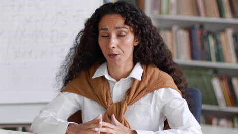 female professor giving an online lecture from a library or classroom
