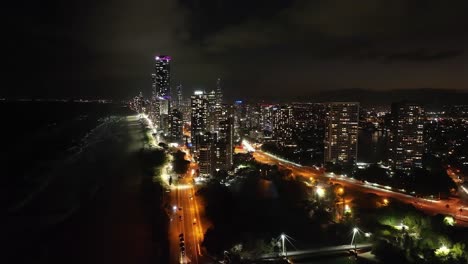 Hoving-over-the-iconic-Gold-Coast-cityscape,-blinking-lights-shining-out-over-sparkling-seas