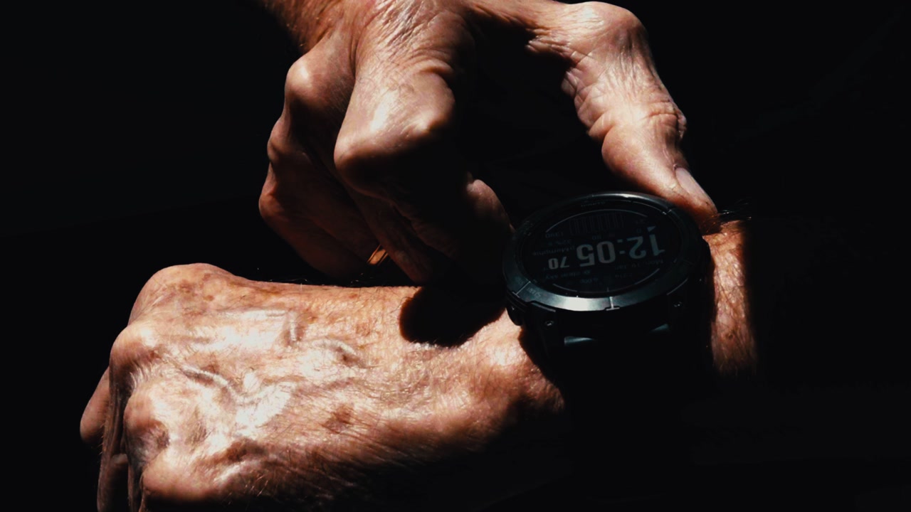 weathered senior citizen hands operate a new exercise technical watch and navigate through the menu, close-up of hands only, dramatic shot
