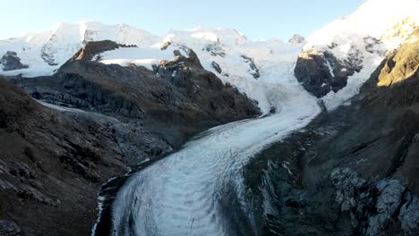 Sobrevuelo-Aéreo-Al-Final-Del-Glaciar-Morteratsch-En-Engadin,-Suiza-Al-Amanecer-Con-Una-Panorámica-Desde-Algunos-De-Los-Picos-Más-Altos-De-Los-Alpes-Suizos-Como-Piz-Bernina,-Piz-Palu