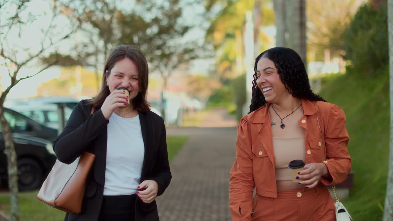 Two women walking and talking while holding coffee cups