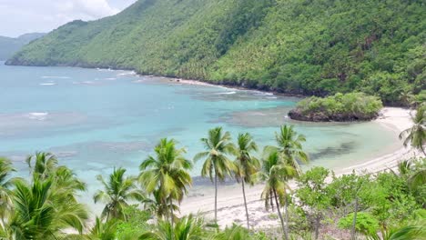 aerial approaching shot of empty playa ermitano beach with coral reef and green coastline in samana, dominican republic