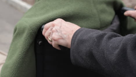 elderly woman pushing wheelchair for husband