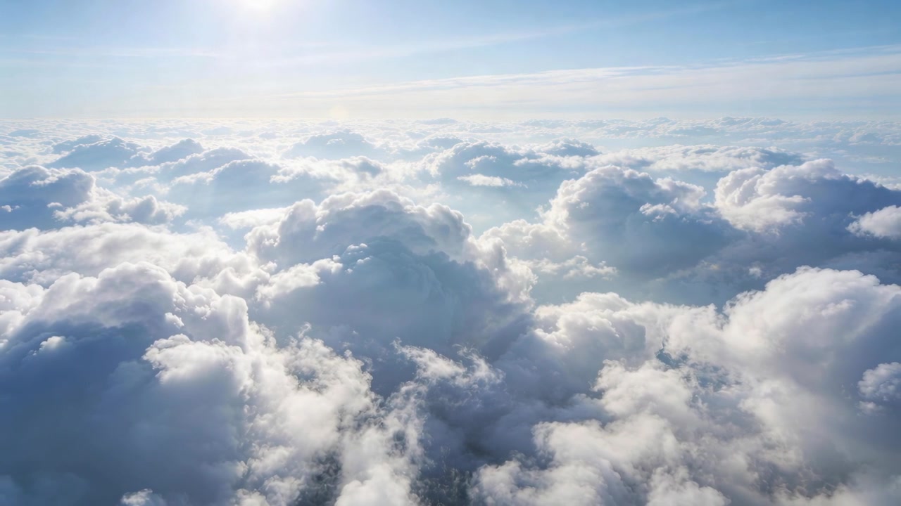 Memulai meluncur, drone bergerak turun di atas awan, menangkap awan kumulus yang disinari matahari dengan matahari di kiri atas.